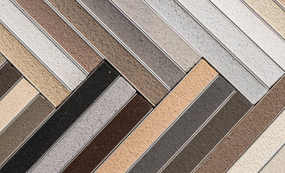 Tile grout sample board with herringbone pattern showing neutral-toned tiles and metallic silver grout dividers.