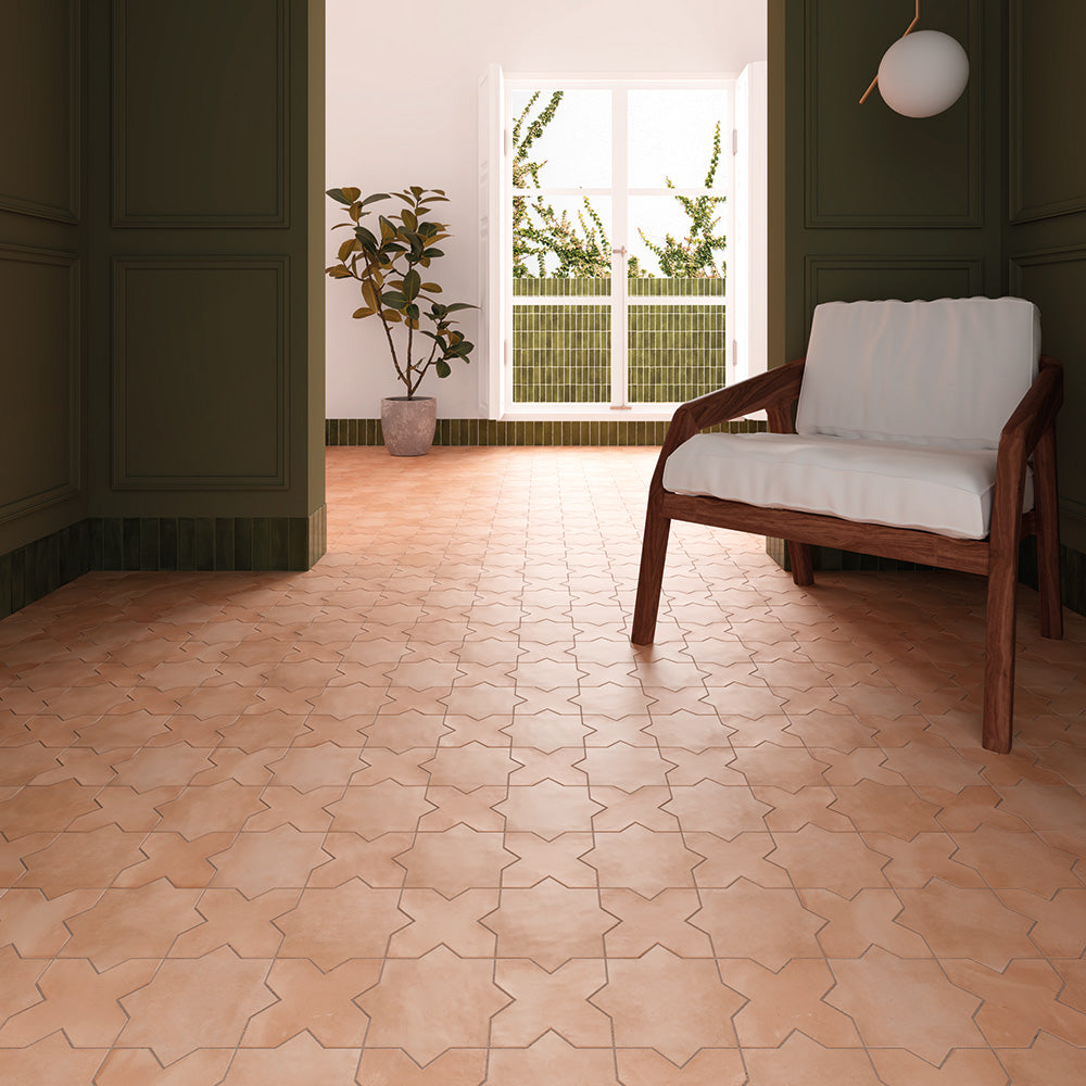 Sunlit entryway featuring warm terracotta star-and-cross floor tiles, with dark green paneled walls and a lounge chair.
