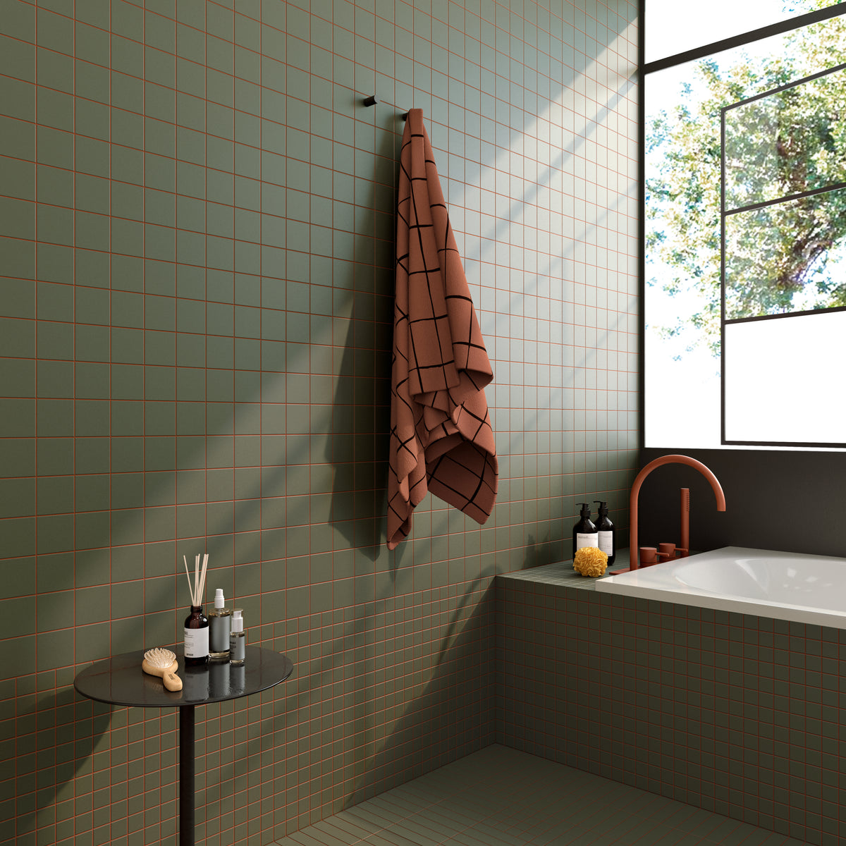 Modern bathroom with sage green square tiles and reddish-brown grout, featuring a built-in bathtub, natural light, and minimalist design