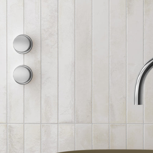 Bali White 2x16 glossy ceramic tile installed vertically on a bathroom shower wall with chrome fixtures
