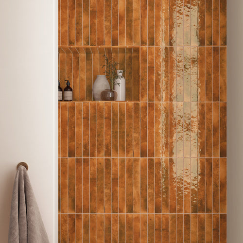 Bali Ginger 2x16 glossy ceramic tile installed vertically on a shower wall with a warm amber-toned finish
