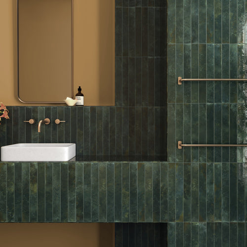 Bali Isle Of Pines 2x16 glossy ceramic tile installed on a bathroom wall with deep green variation