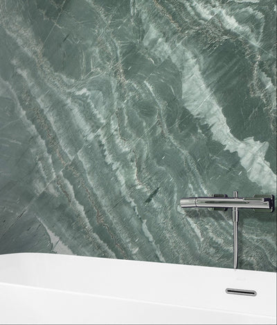 Green veined marble wall with white bathtub showcasing ElitTile Natural Stone Slabs in modern bathroom design