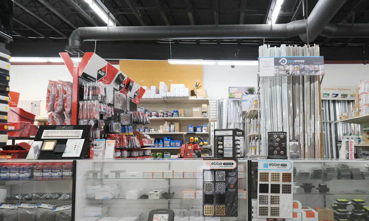 ElitTile showroom interior displaying tile tools, drain covers, trim profiles, adhesives, and installation supplies on shelves and displays