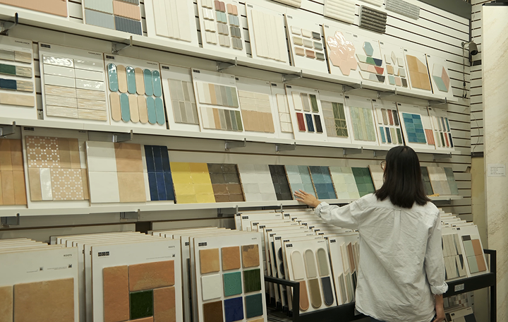 Customer browsing tile samples at ElitTile showroom in Los Angeles, featuring rows of ceramic and porcelain tiles on white shelves.